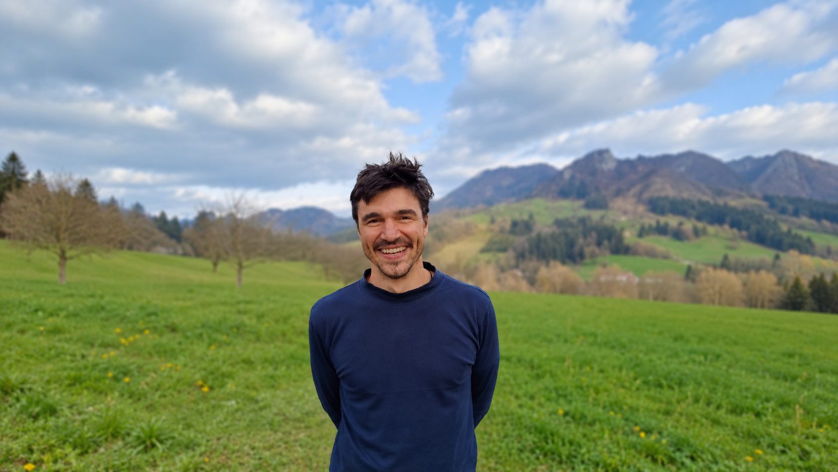 Viktor auf einer Wiese vor einer Berglandschaft